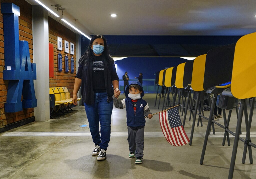 Lisa Carrera, maestra de historia jubilada, con su nieto Maverick, de 2 años, sale de votar en el estadio Dodger de Los Ángeles, 2 de noviembre de 2020. (AP)