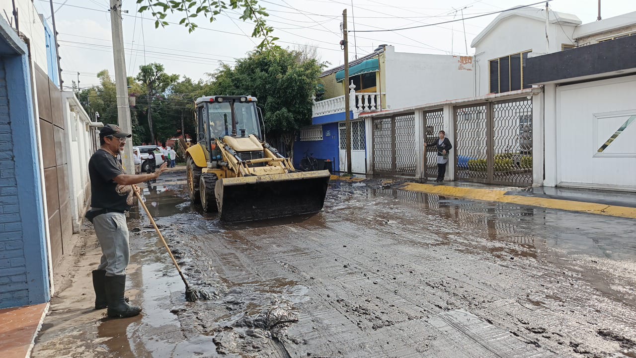 Voluntarios y funcionarios limpiando viviendas en Coacalco tras el desbordamiento del canal pluvial.