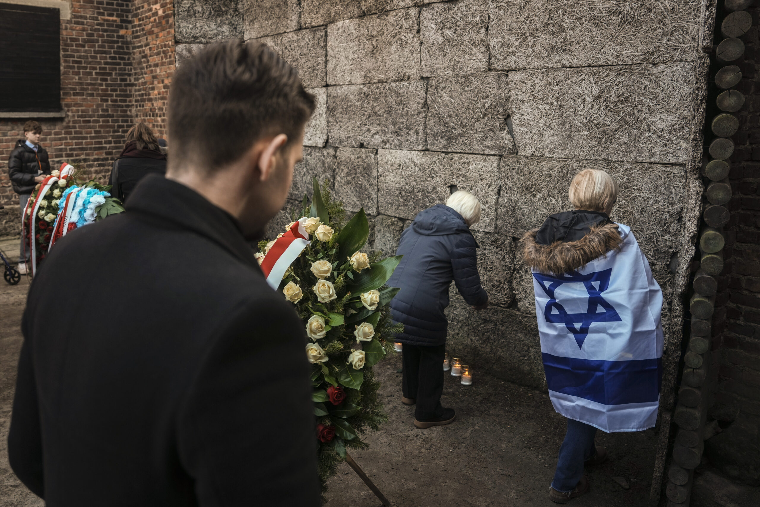Sobrevivientes y familiares colocan velas junto al Muro de la Muerte durante una ceremonia en el antiguo campo nazi de concentración y exterminio de Auschwitz-Birkenau. Foto:  AP.