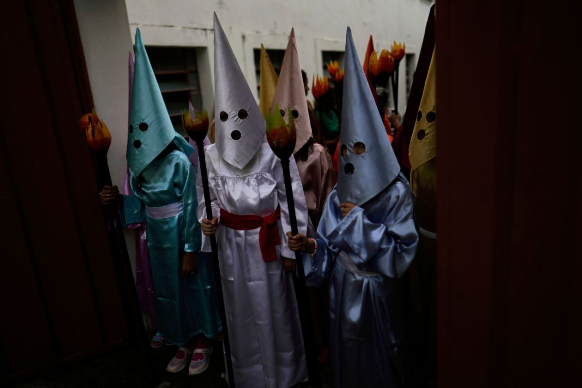 Jóvenes vestidos de nazarenos participan en una procesión infantil con antorchas durante la Semana Santa, en Goias, Brasil.