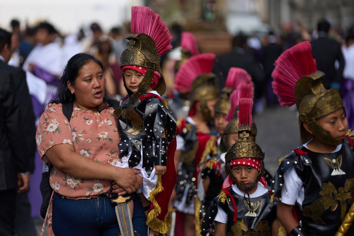 Una mujer lleva a un niño vestido de soldado romano en brazos, durante una procesión de Semana Santa en Antigua, Guatemala.